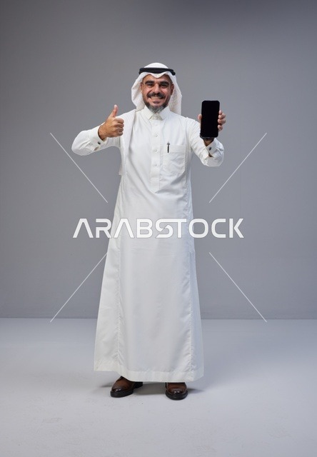 Saudi Man in Traditional Thobe Holding Blank Smartphone