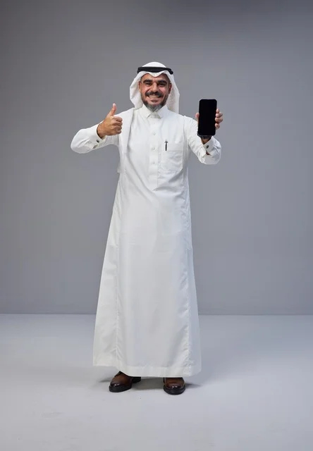 رجل سعودي بالزي التقليدي يحمل هاتفاً بشاشة فارغة