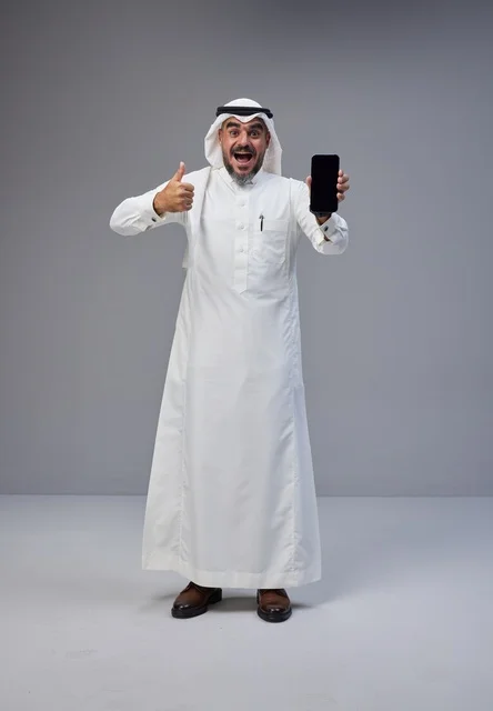 رجل سعودي مع هاتف ذكي بشاشة فارغة وإشارة الإبهام
