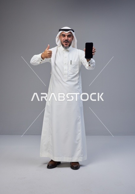 Saudi Man in Traditional Thobe Holding Blank Smartphone