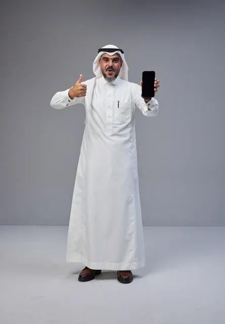 رجل سعودي بالزي التقليدي يحمل هاتفا ذكيا