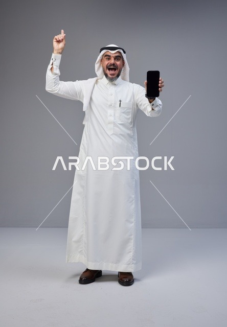 Saudi Man Holding Blank Smartphone Screen and Pointing Up