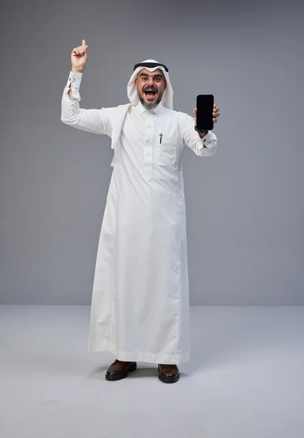 رجل سعودي يحمل هاتف بشاشة فارغة ويشير للأعلى