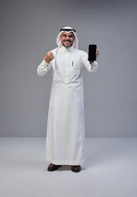 رجل سعودي بالزي التقليدي يحمل هاتفاً بشاشة فارغة