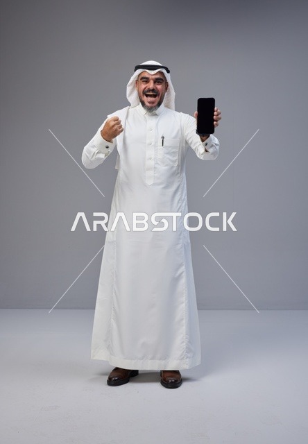 Saudi Man Holding Blank Smartphone in Victory Pose