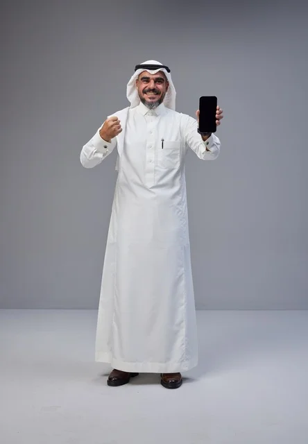 رجل سعودي بالزي التقليدي يحمل هاتف بشاشة فارغة