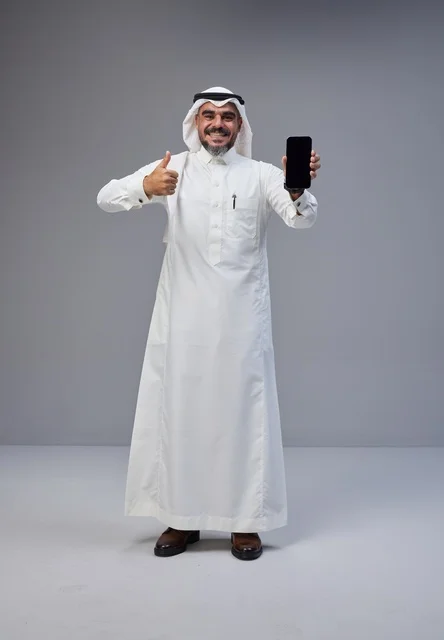 رجل سعودي يحمل هاتف بشاشة فارغة مع إشارة الإعجاب
