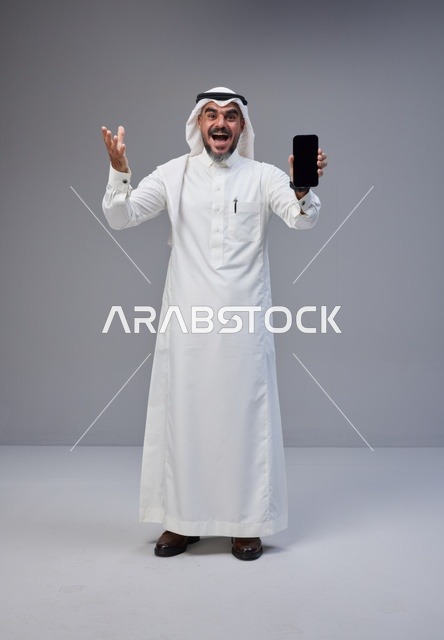 Saudi Man in Traditional Thobe Holding Blank Smartphone
