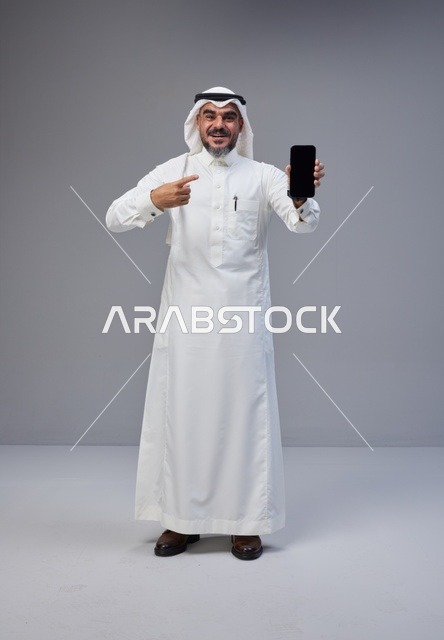 Saudi Man in Thobe Pointing at Smartphone Screen