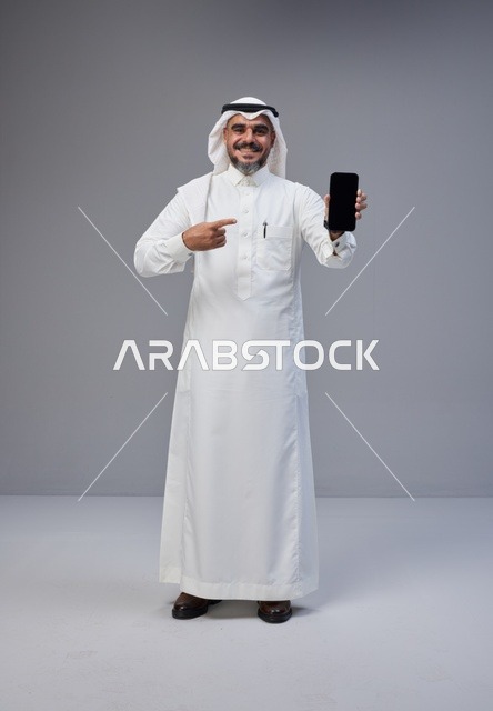 Saudi Man in Thobe Pointing at Blank Smartphone Screen