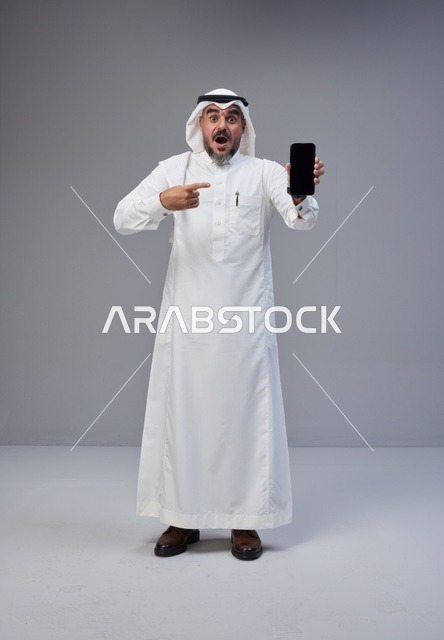 Saudi Man Holding Blank Smartphone with Shocked Face