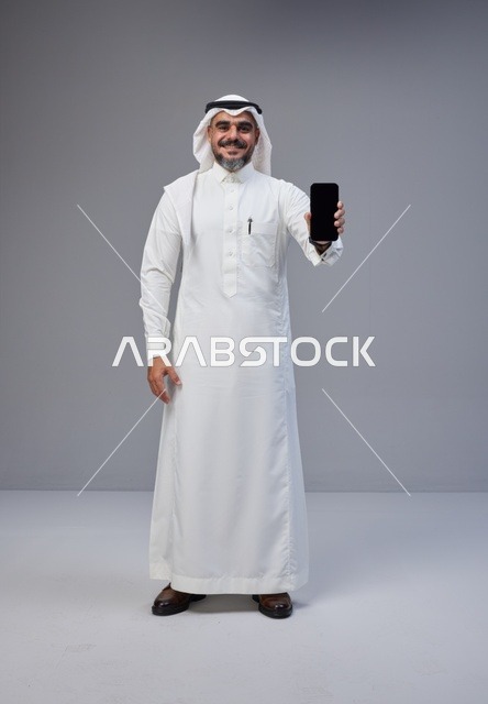 Saudi Man in Thobe Holding Blank Smartphone Screen