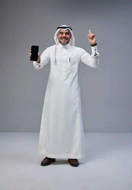رجل سعودي بالزي التقليدي يحمل هاتفاً ذكياً