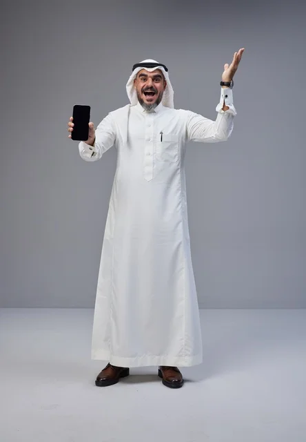 رجل سعودي يحمل هاتف ذكي بشاشة فارغة في الاستوديو