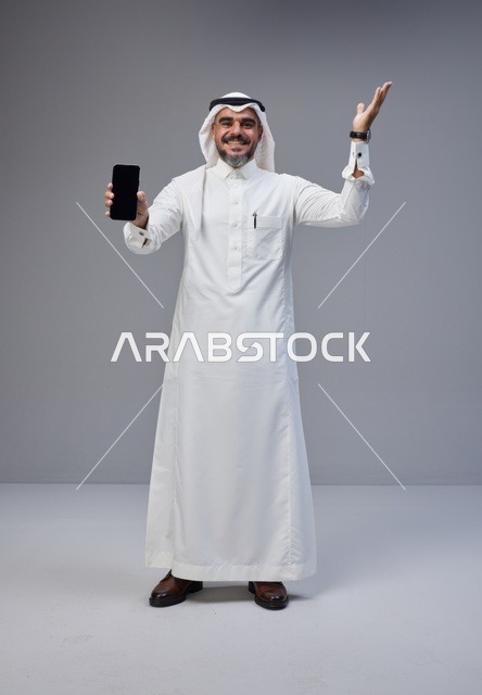 Saudi Man Holding Smartphone with Blank Screen in Studio