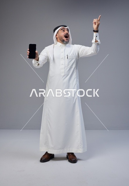 Saudi Man with Smartphone Pointing Upwards Studio