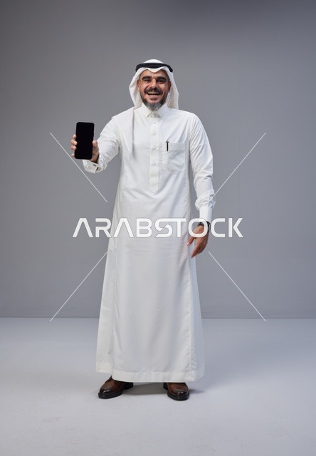 Saudi Man in Thobe Holding Blank Smartphone