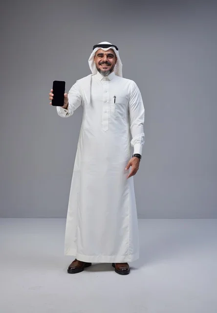 رجل سعودي بالزي التقليدي يحمل هاتفاً بشاشة فارغة