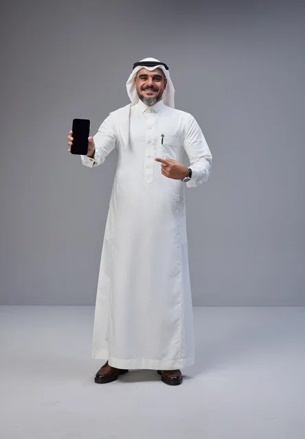 رجل سعودي بالزي التقليدي يحمل هاتفاً بشاشة فارغة