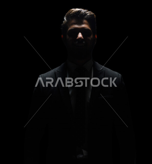 بورتريه لرجل أعمال عربي يرتدي بدلة أنيقة ، يقف بإستقامه , ينظر إلى الكاميرا ، الوقوف بثقه , ملامح مخفية ضبابية ، خلفية سوداء