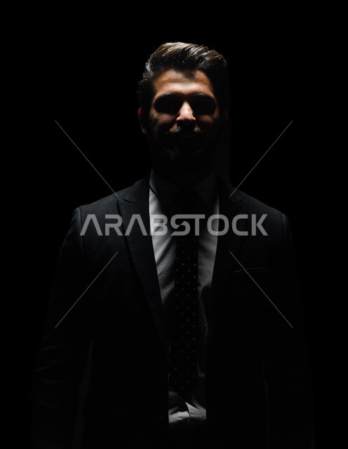بورتريه لرجل أعمال عربي يرتدي بدلة أنيقة ، يقف بإستقامه , ينظر إلى الكاميرا ، الوقوف بثقه , ملامح مخفية ضبابية ، خلفية سوداء