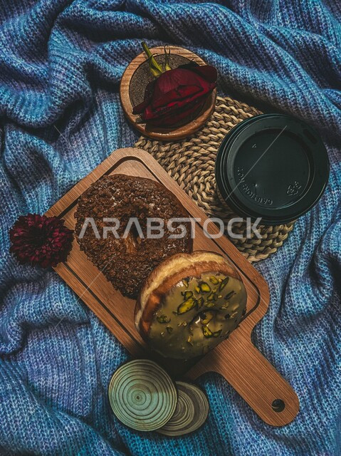 صورة من أعلى لقهوة وحلا الدونات المدور فوق لوح خشبي مصورة على شرشف أزرق ، حلويات وسكريات ، أفكار للتزيين ، ضيافة وإستقبال ، فن تصوير الطعام بشكل إحترافي