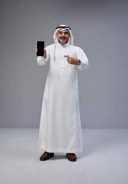 رجل سعودي بالزي التقليدي يحمل هاتفا بشاشة فارغة
