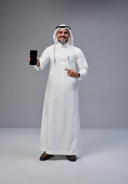 رجل سعودي بالثوب التقليدي يحمل هاتفاً بشاشة فارغة