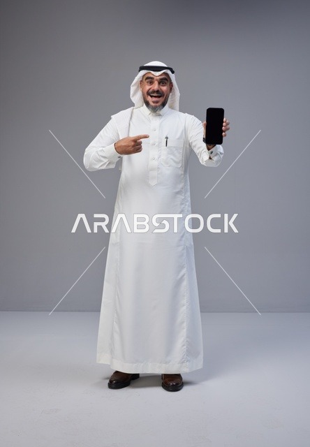 Saudi Man in Traditional Thobe Pointing to Smartphone