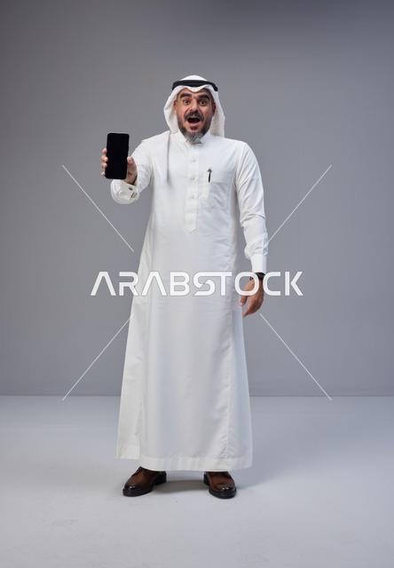 Saudi Man in Thobe Holding Blank Smartphone Screen