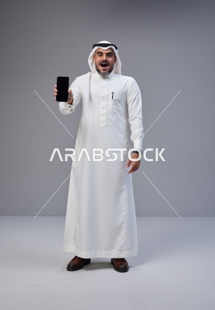 Saudi Man in Traditional Thobe Holding Blank Smartphone