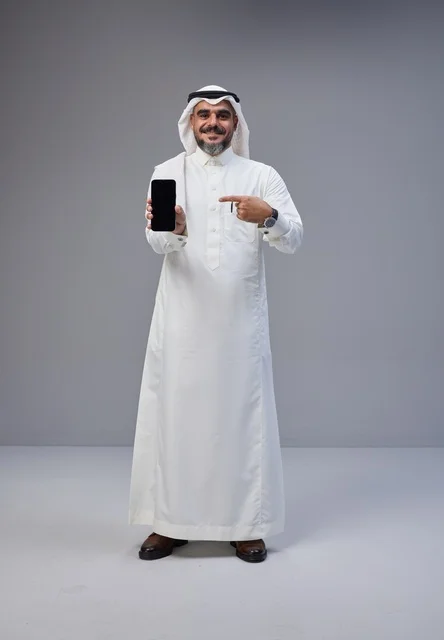رجل سعودي يحمل هاتفاً ذكياً بشاشة فارغة