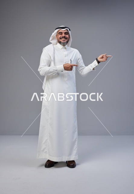 رجل سعودي بالثوب التقليدي يشير بيده في الاستوديو