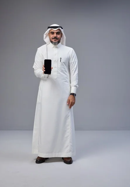 رجل سعودي يحمل هاتفاً بشاشة فارغة
