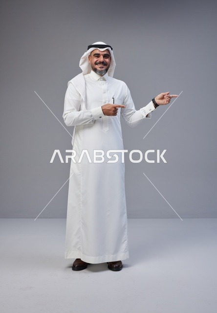 Saudi Man in Traditional Thobe Pointing Side in Studio