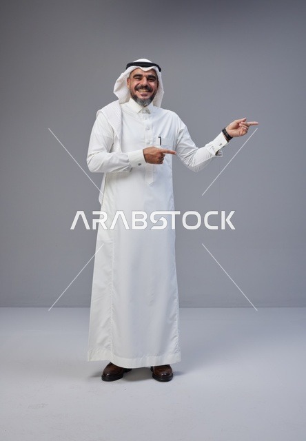 رجل سعودي بالزي التقليدي يشير بيده في الاستوديو