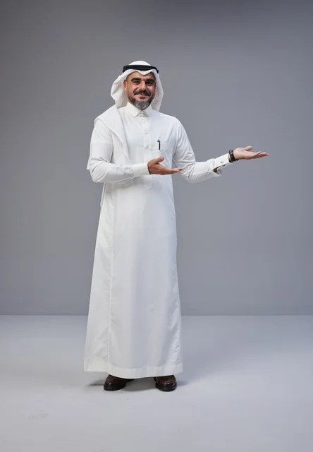 رجل سعودي بالزي التقليدي يشير بيده على خلفية رمادية