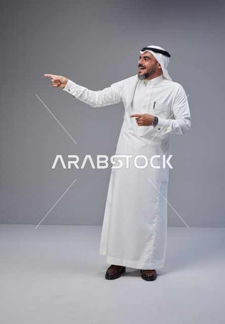 رجل سعودي بالزي التقليدي يشير بيده في الاستوديو