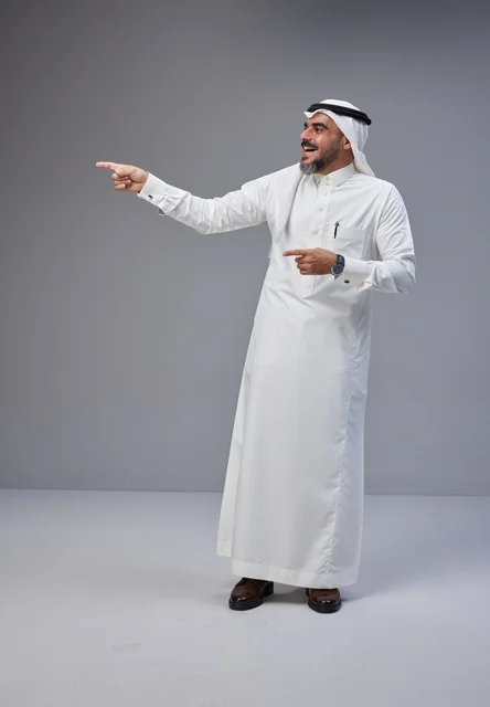 رجل سعودي بالزي التقليدي يشير بيده في الاستوديو