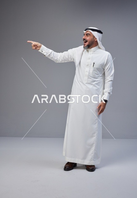 Excited Saudi Man Pointing in Traditional Clothing Studio