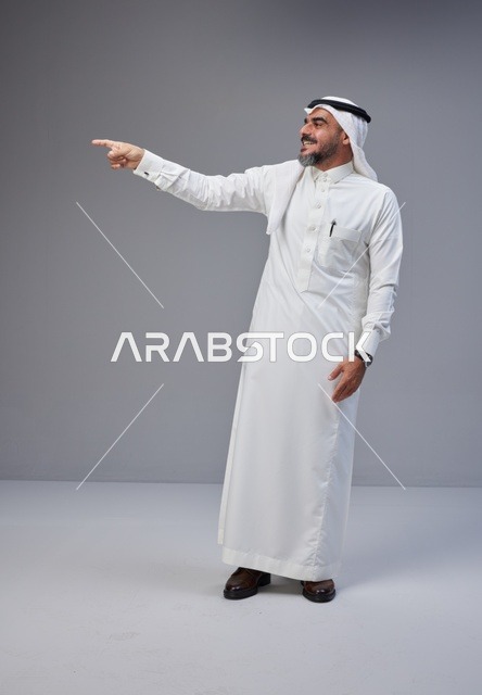 رجل سعودي بالزي التقليدي يشير بيده في الاستوديو