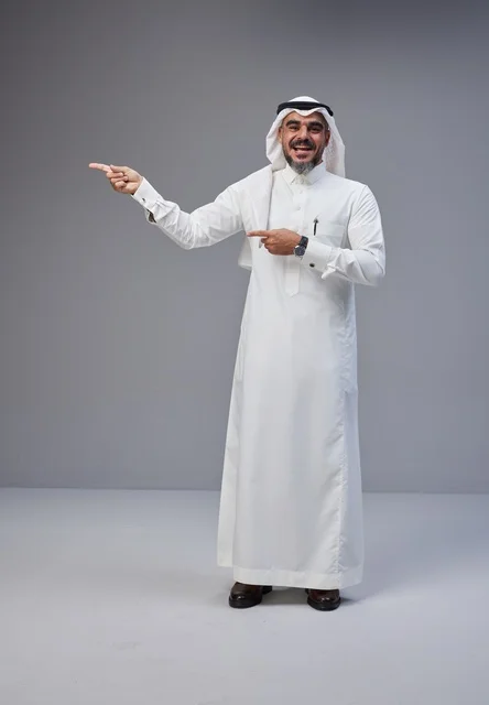 رجل سعودي مبتسم يشير إلى مساحة فارغة في الاستوديو