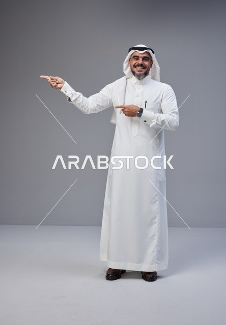Saudi Man in Traditional Thobe Pointing Left in Studio