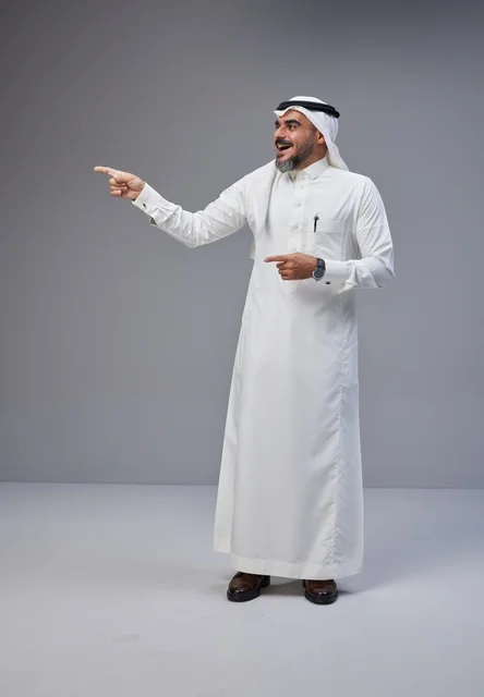 رجل سعودي بالزي التقليدي يشير بيده بخلفية رمادية