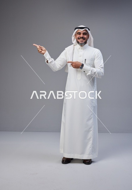 Saudi Man in Traditional Thobe Pointing on Gray Background