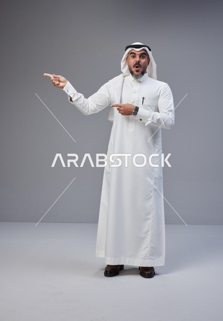 رجل سعودي بالثوب التقليدي يشير بتعبير وجه مندهش