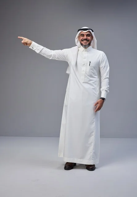 Smiling Saudi Man in Traditional Thobe Pointing in Studio