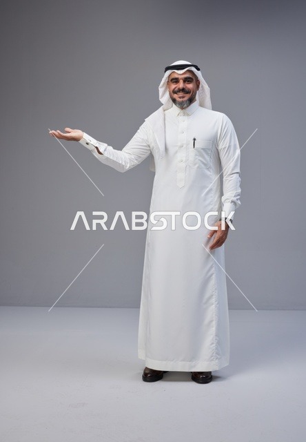 رجل سعودي يرتدي الثوب التقليدي يشير بيده في الاستوديو
