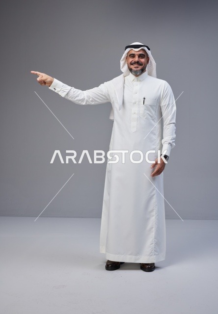 Saudi Man in Traditional Thobe Pointing on Gray Background