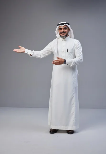 رجل سعودي بالزي التقليدي يبتسم ويشير بيده في الاستوديو